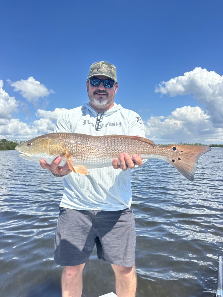 Angler holding a large Redfish caught on a Punta Gorda fishing charter with Reel Fishing Charters.