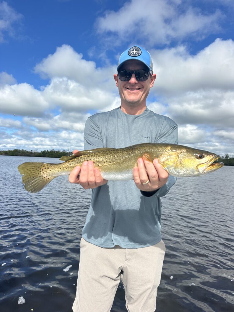 Angler holding a Speckled Trout caught on a Boca Grande fishing charter with Reel Fishing Charters.