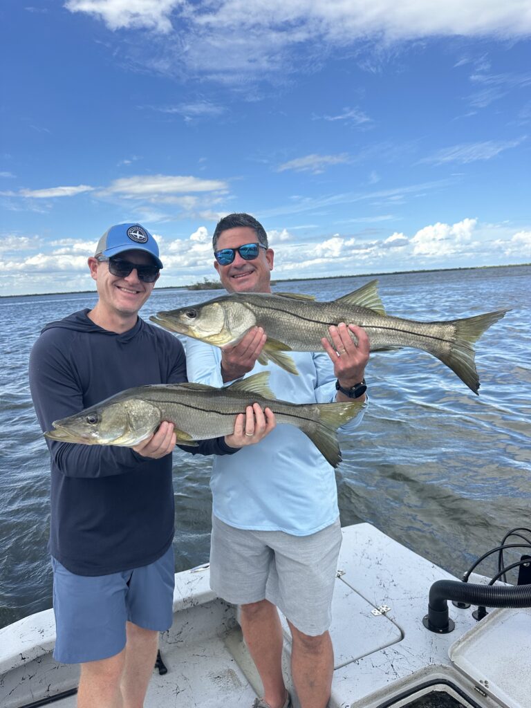 Two anglers holding Snook caught on a Boca Grande fishing charter with Reel Fishing Charters in Southwest Florida.