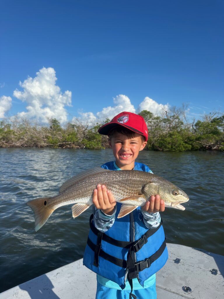 Kid Holding Redfish on Boca Grande Family Fishing Trip Young boy holding a redfish during a family fun fishing charter in Boca Grande, Florida
