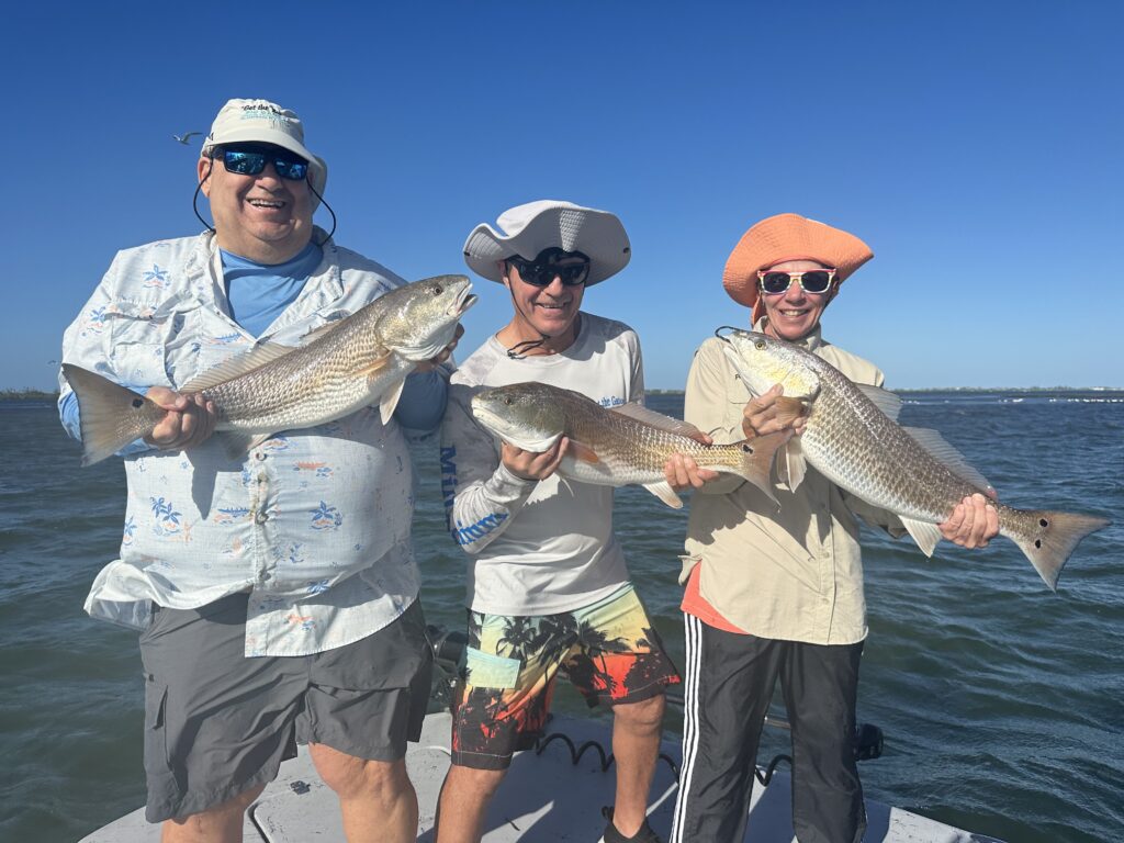 Boca Grande Fishing Charters-Reelfishing Happy anglers holding redfish on a Boca Grande fishing charter with Reelfishing.