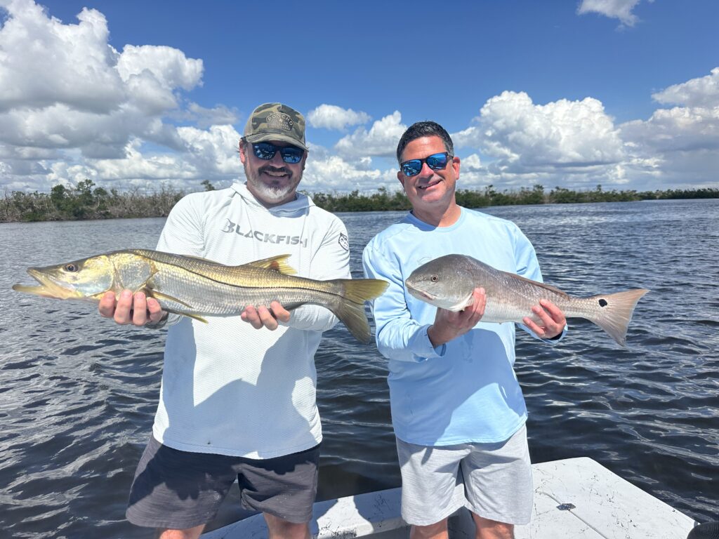 Inshore Fishing Charters – Snook & Redfish | Punta Gorda & Boca Grande Two anglers holding a Snook and a Redfish on Charlotte Harbor during an inshore charter with ReelFishing Charters (Punta Gorda-Boca Grande).