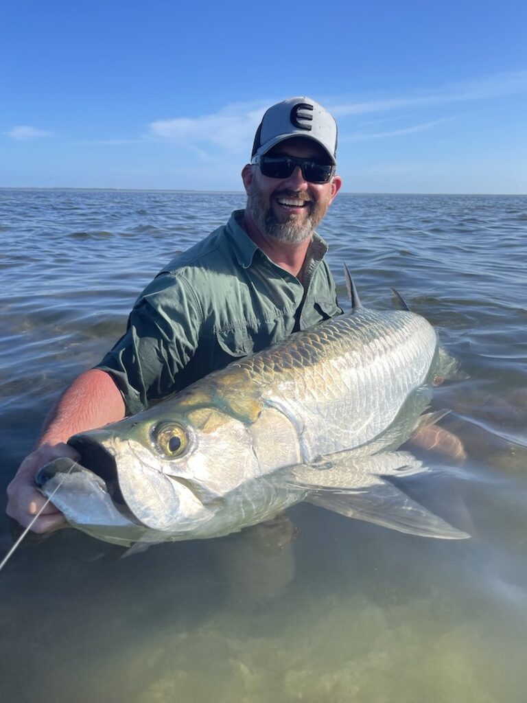 Boca Grande Tarpon Fishing – Trophy Tarpon Release in Shallow Water Angler holding a large Tarpon in shallow water during a Boca Grande Tarpon fishing charter with ReelFishing Charters.