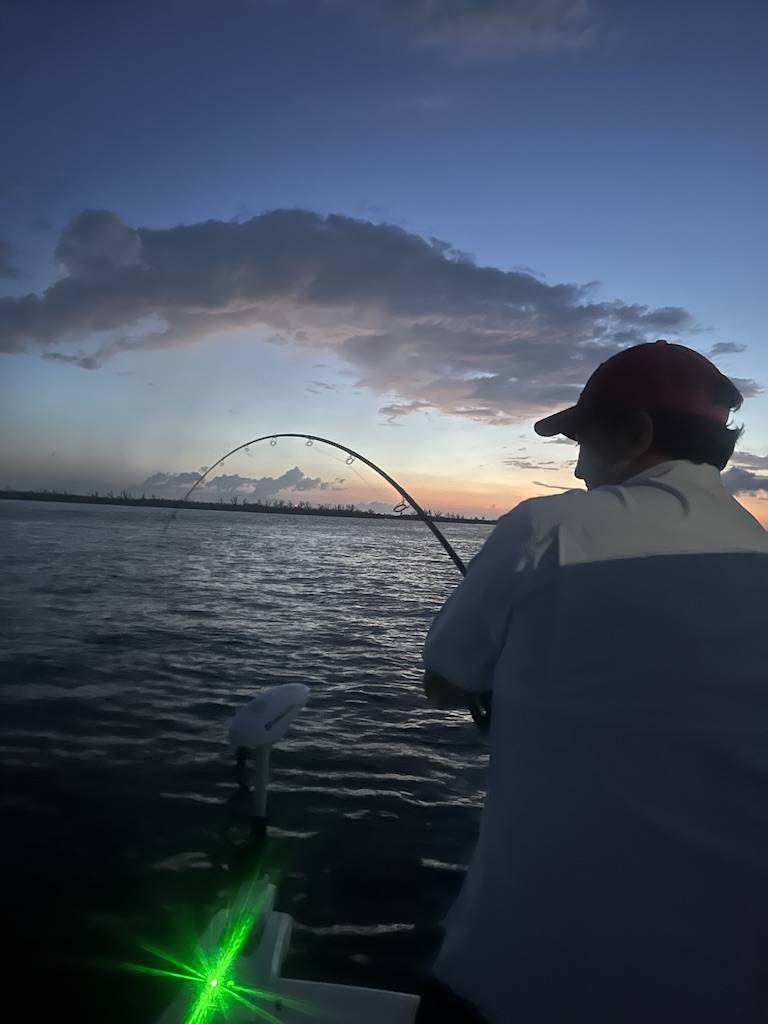 Boca Grande Tarpon Fishing Charter at Sunset Angler fighting a tarpon at sunset during a Boca Grande fishing charter in Florida
