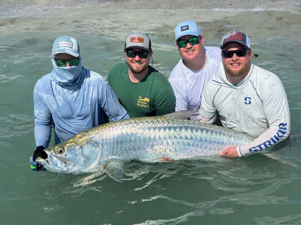 Boca Grande Tarpon Fishing Charter – Trophy Catch with ReelFishing Charters Group of anglers holding a large trophy tarpon during a Boca Grande fishing charter with ReelFishing Charters.