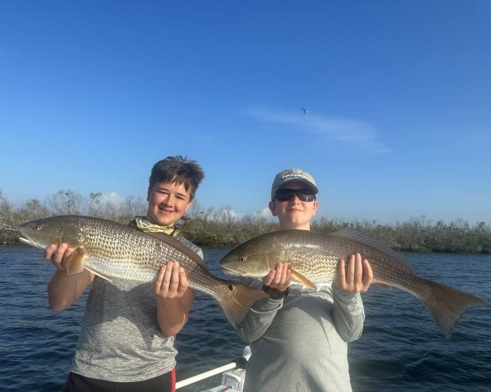 Family Redfish Fishing Charter Near Port Charlotte Kids holding redfish during a family fishing charter serving Port Charlotte in Charlotte Harbor, Florida
