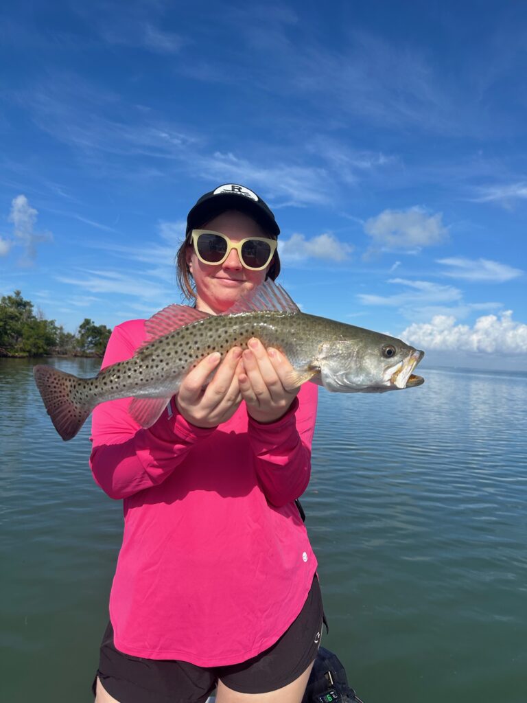 Angler holding a speckled trout caught on the Punta Gorda grass flats during a December inshore fishing trip.