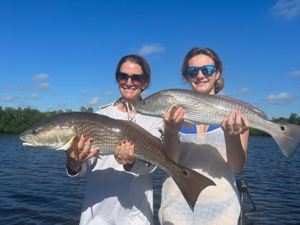 Two anglers holding redfish caught during a January 2026 inshore fishing report with ReelFishing Charters in Punta Gorda.