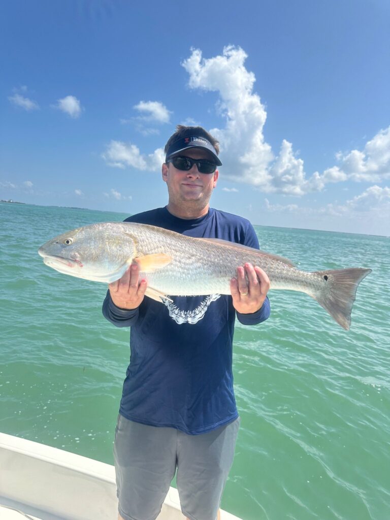 Charlotte Harbor Redfish Fishing β August 2026 Angler holding a slot-sized redfish caught in Charlotte Harbor during an August fishing charter with ReelFishing Charters.