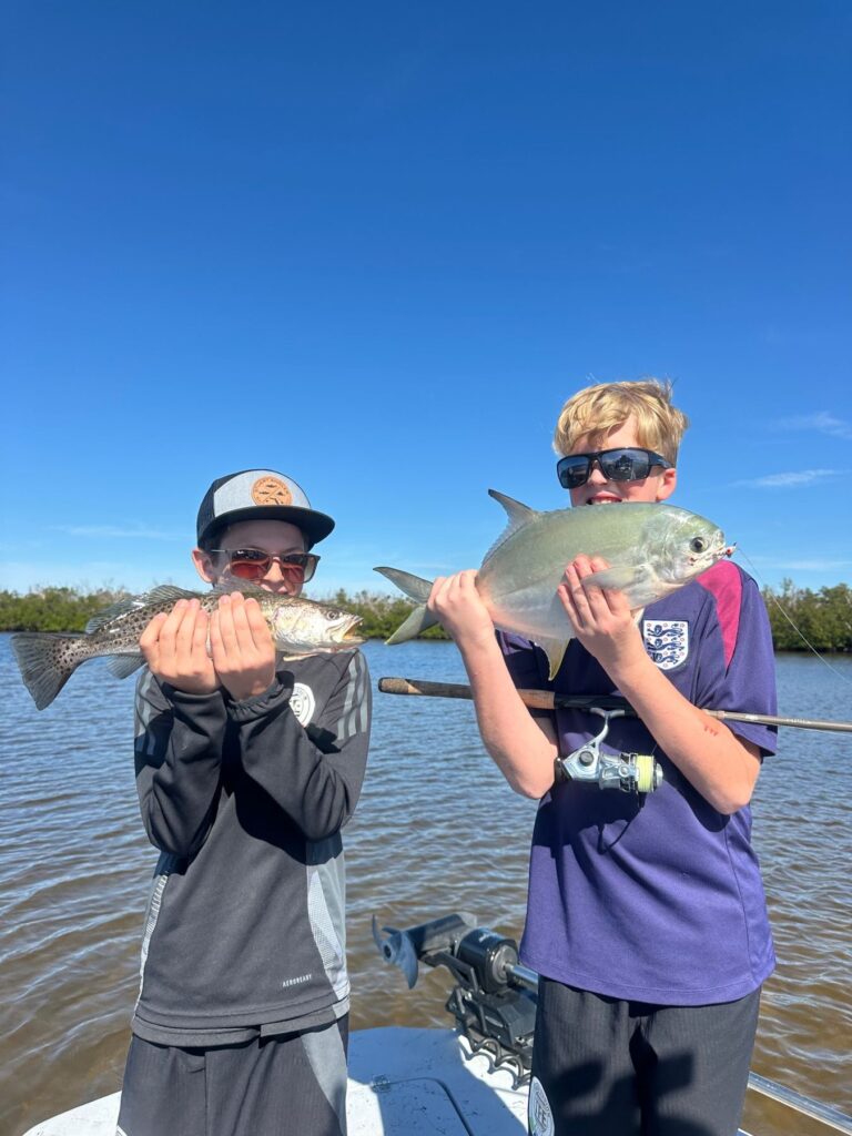 Fall Family Fishing in Charlotte Harbor Young anglers holding a speckled trout and pompano during a Charlotte Harbor fishing trip