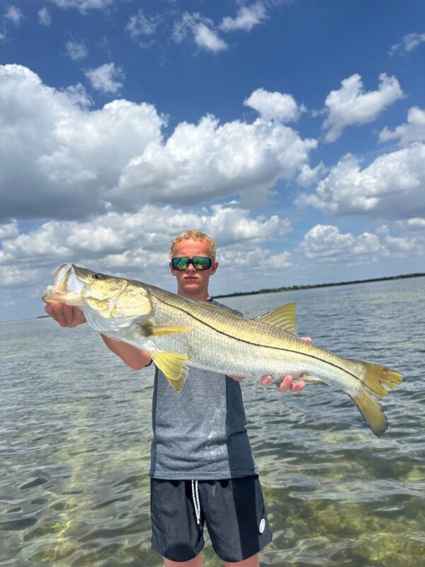 Punta Gorda Snook Fishing Charter Young angler holding a large Snook on a Punta Gorda fishing charter